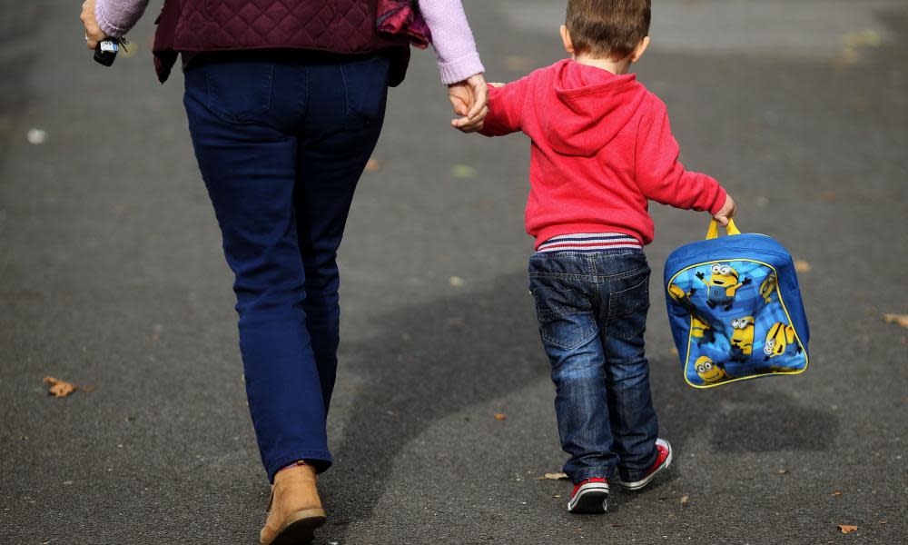 Young boy holds a carer's hand