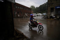 A child rides a motorcycle in the rain on Friday, Aug. 5, 2022, in Fleming-Neon, Ky. (AP Photo/Brynn Anderson)