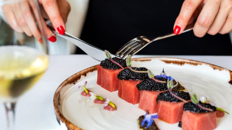 Woman's hands eating tuna with caviar