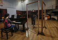 Ylenia Labanca, left, plays piano with a singer Yidan Fu, behind a transparent panel to curb the spread of COVID-19, during a lesson at the Giuseppe Verdi Music Conservatory, in Milan, Italy, Thursday, April 29, 2021. Whatever the instrument, flute, violin or drums, students at Italy's oldest and largest music conservatory have been playing behind plexiglass screens during much of the pandemic as the Conservatory found ways to preserve instruction throughout Italy’s many rolling lockdowns. (AP Photo/Antonio Calanni)