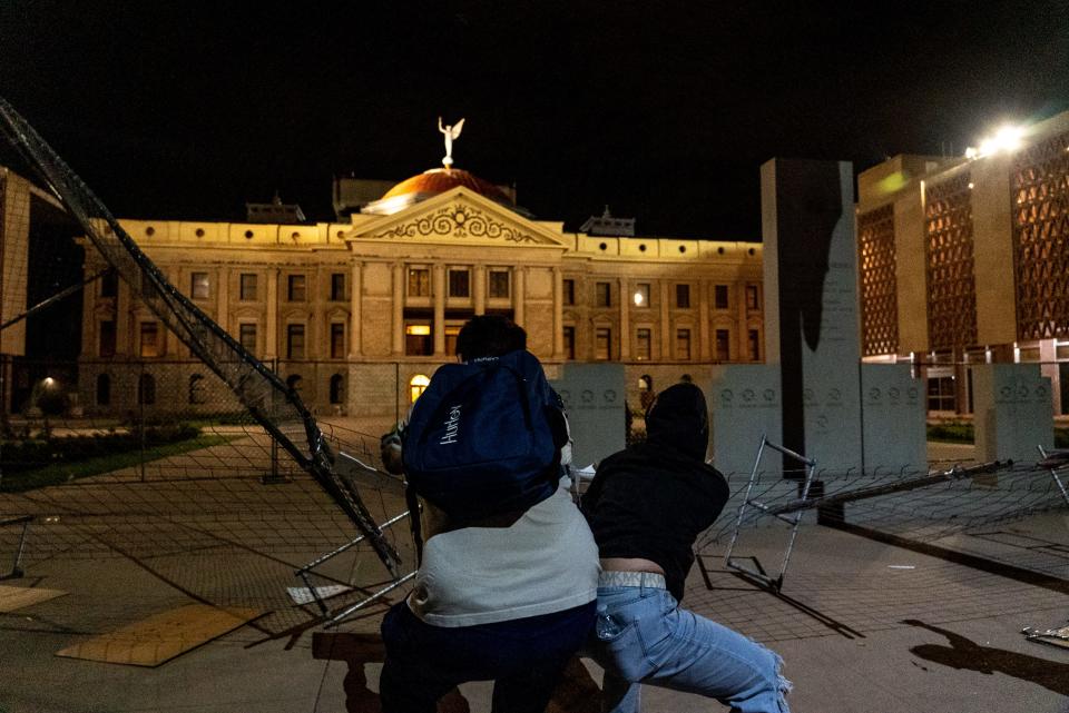 Protesters pull down a gate around the perimeter of the Arizona Capitol during an abortion-rights protest following the Supreme Court's decision to overturn Roe v. Wade. Arizona State Troopers arrested at least a dozen protesters after the gate was pulled down.