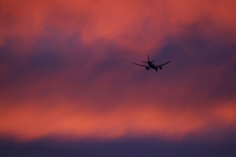 FILE PHOTO: A plane flies in a red sky above London