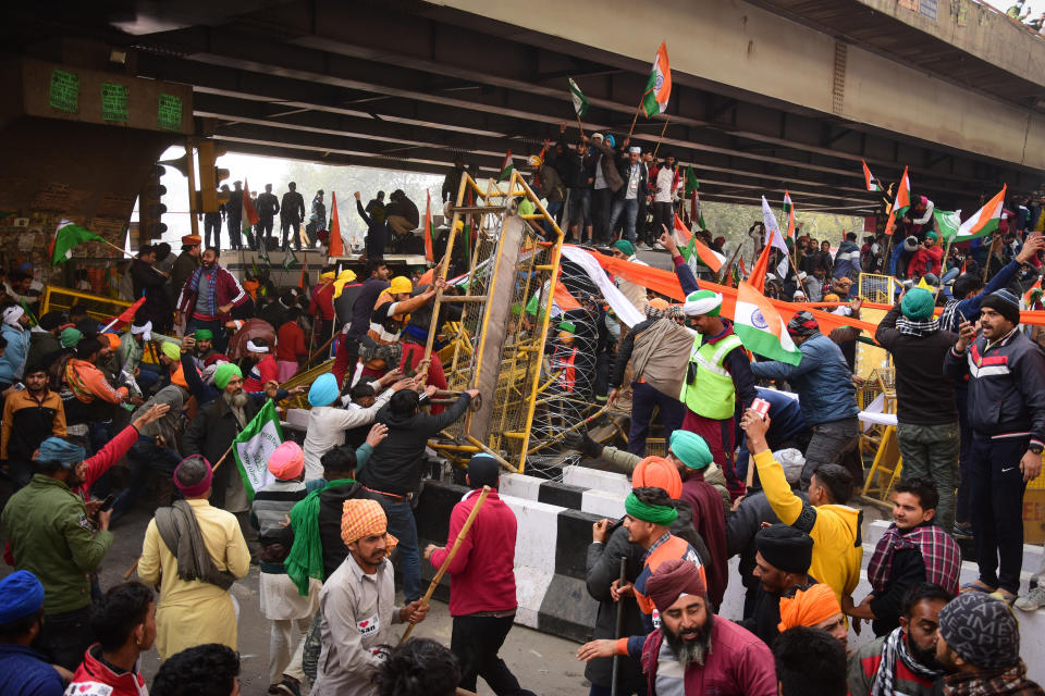 DELHI, INDIA - 2021/01/26: Protesters remove police barricades from the road during the demonstration. Farmers protesting against agricultural reforms breached barricades and clashed with police in the capital on the India's 72nd Republic Day. The police fired tear gas to restrain them, shortly after a convoy of tractors trundled through the Delhi's outskirts. (Photo by Manish Rajput/SOPA Images/LightRocket via Getty Images)