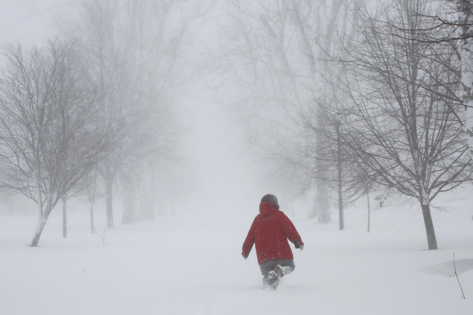 A person walks on the street as a winter storm rolls through Western New York Saturday, Dec. 24, 2022, in Amherst N.Y. A battering winter storm has knocked out power to hundreds of thousands of homes homes and businesses across the United States on Saturday. It left millions more to worry about the prospect of further outages and crippled police and fire departments. (AP Photo/Jeffrey T. Barnes)