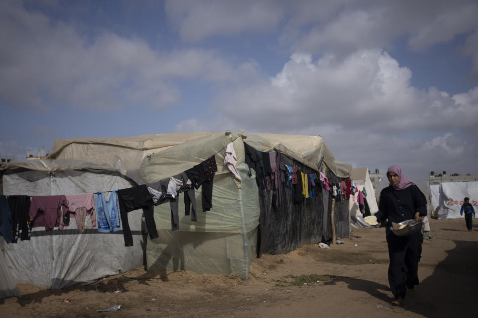 Palestinians displaced by the Israeli ground offensive on the Gaza Strip walk at the makeshift tent camp in Rafah on Tuesday, Jan. 23, 2024. (AP Photo/Fatima Shbair)