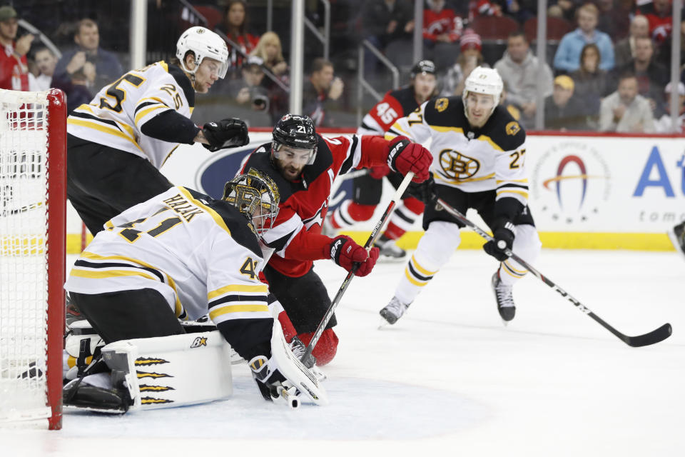 New Jersey Devils right wing Kyle Palmieri (21) tries to force the puck in as Boston Bruins goaltender Jaroslav Halak (41) defends during the second period of an NHL hockey game, Tuesday, Dec. 31, 2019, in Newark, N.J. Bruins defenseman Brandon Carlo (25) and John Moore (27) watch. (AP Photo/Kathy Willens)