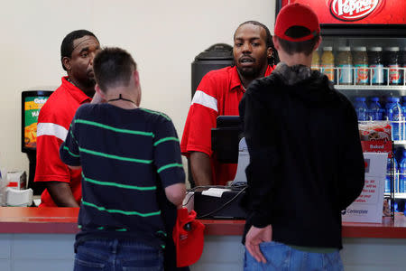 Two young men with "Make America Great Again" hats speak to concession workers before the National Rifle Association (NRA) annual leadership forum in Dallas, Texas, U.S., May 4, 2018. REUTERS/Lucas Jackson