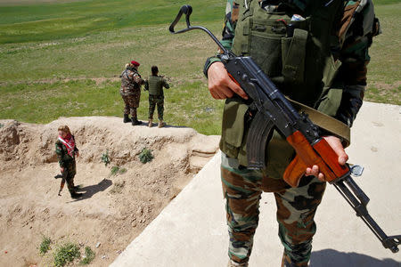 Yazidi female fighter Asema Dahir (R), 21, holds a weapon during a deployment near the frontline of the fight against Islamic State militants in Nawaran near Mosul, Iraq, April 20, 2016. REUTERS/Ahmed Jadallah