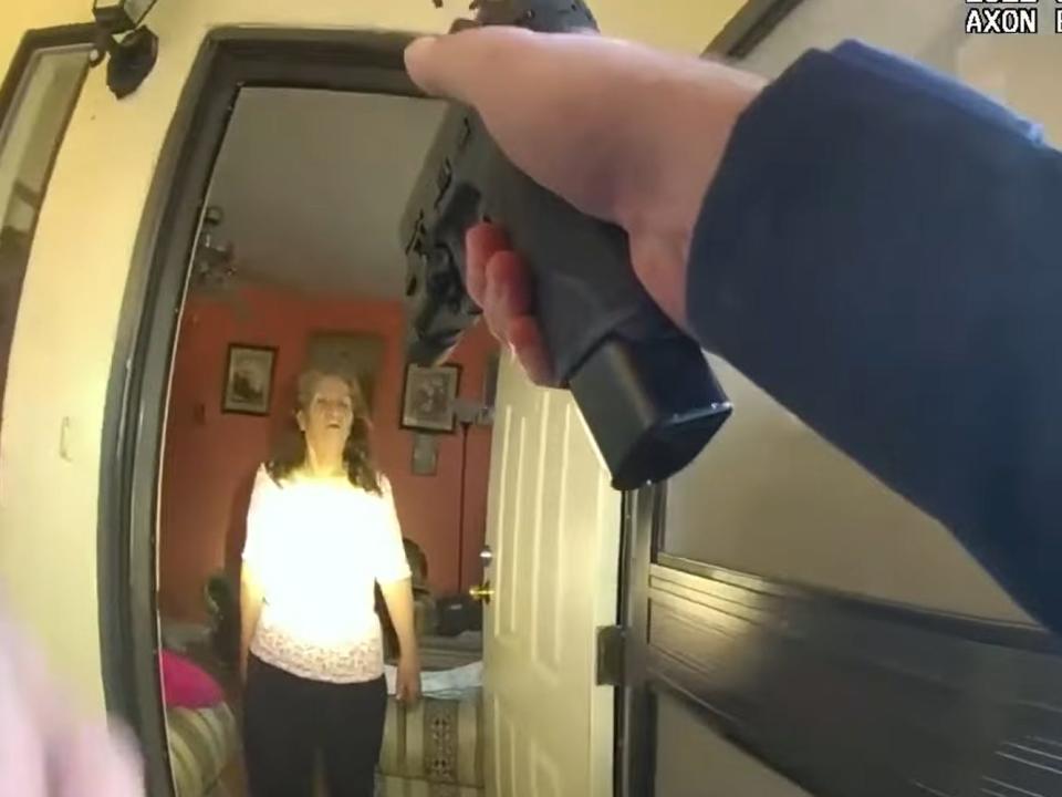 A police officer points a gun at Amelia Baca