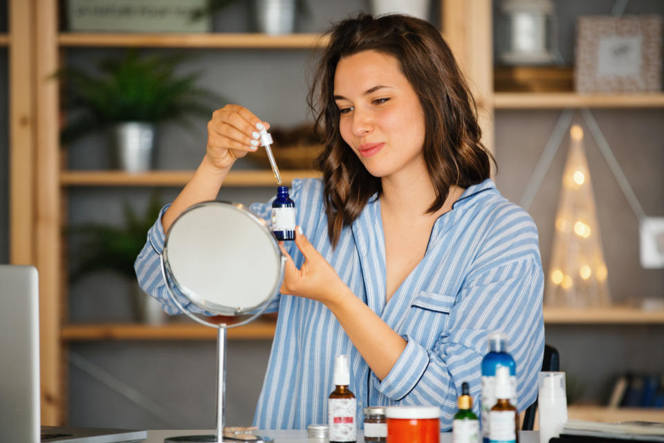 Young woman applying a serum to her face in her evening routine.