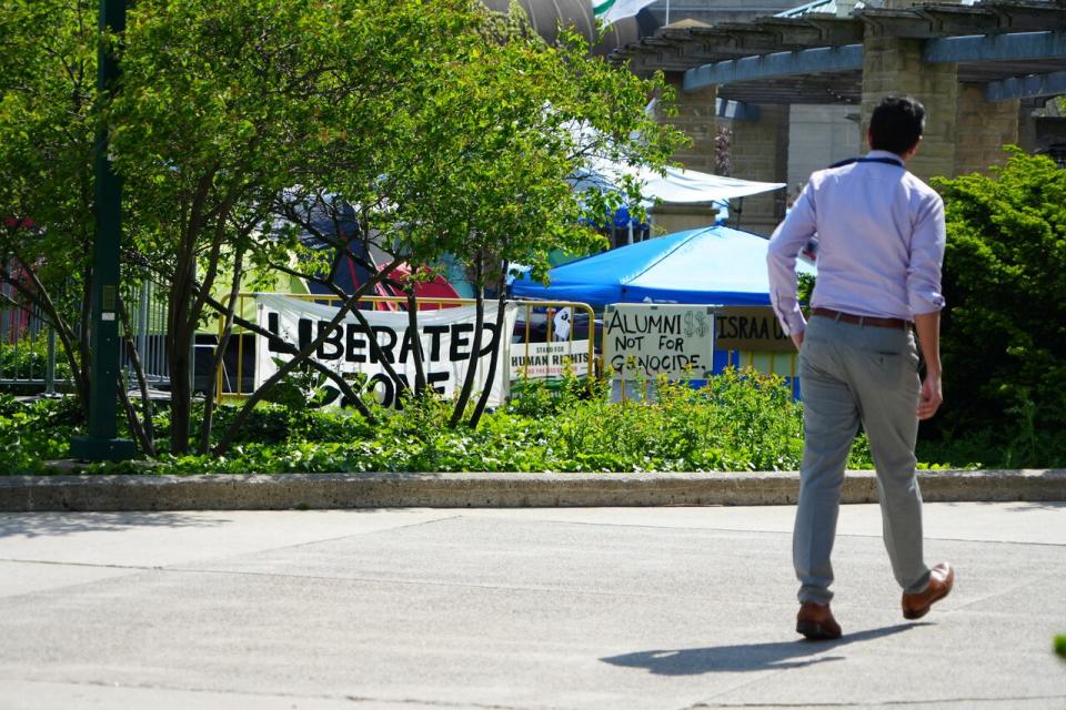 A man walks by a pro-Palestinian protest at Western University in London, Ont., Monday, which has grown to include more than two dozen tents and has taken on a family atmosphere, with young children, including toddlers and even pets. 