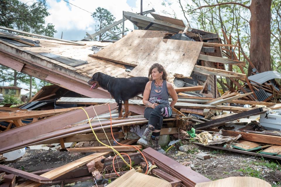 Fran Tribe and her dog Dave sit outside a home destroyed by Hurricane Ida in Houma, La., on Aug. 30, 2021.