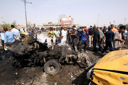 Fuerzas de seguridad y personas se reúnen en el sitio de la explosión de un coche bomba, en Bagdad, Irak. 17 de mayo de 2016. Tres ataques explosivos provocaron la muerte de al menos 63 personas y dejaron más de 100 heridos el martes en Bagdad, dijeron fuentes policiales y médicas. REUTERS/Khalid al Mousily