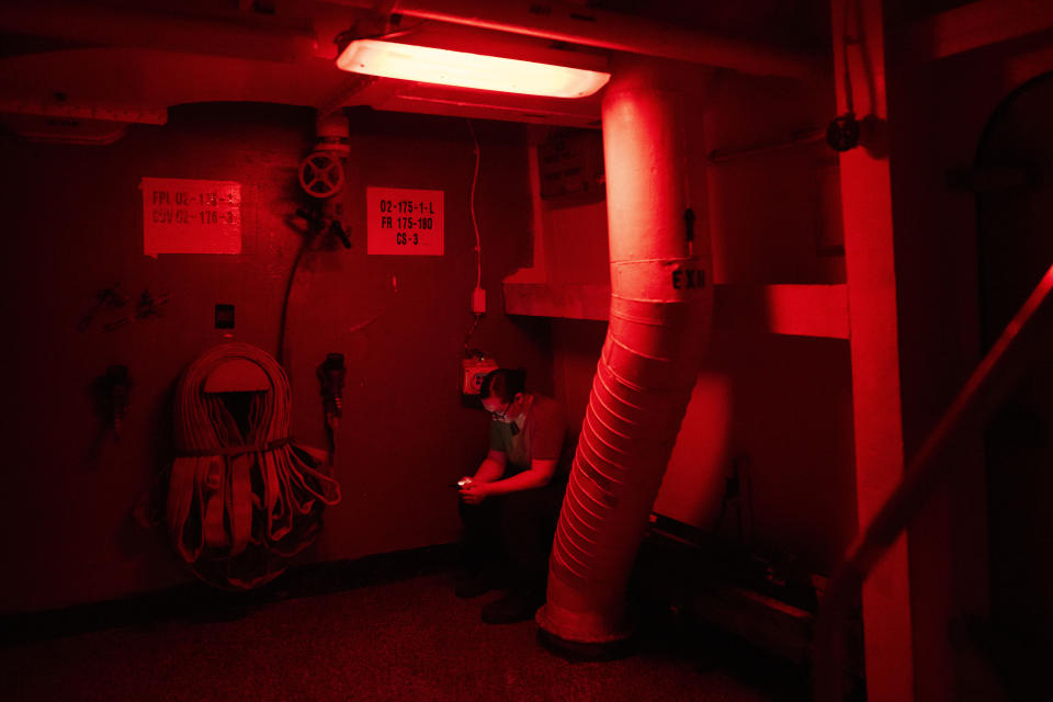 A crew member looks at a cell phone during a break aboard the USS Dwight D. Eisenhower in the Red Sea on Tuesday, June 11, 2024. (AP Photo/Bernat Armangue)