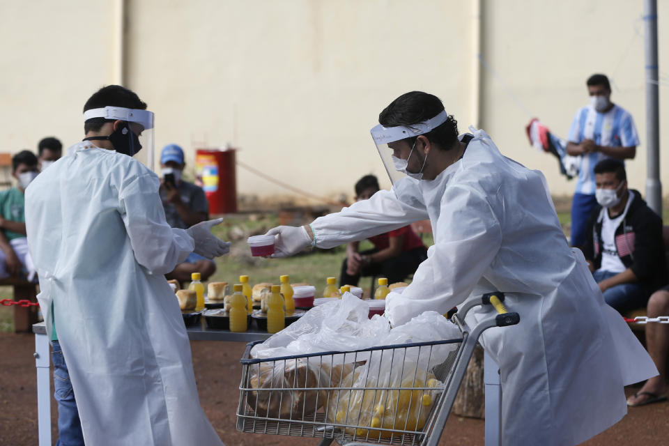 Red Cross volunteers prepare to lunch for people quarantining at a school being used as a government-run shelter where they are required by law to stay and pass two consecutive COVID-19 tests, as a preventive measure amid the COVID-19 pandemic near Ciudad del Este, Paraguay, Wednesday, June 24, 2020. Along with Paraguay's relative isolation, experts credit the country's success at containing COVID-19 with creating a network of quarantine centers in military academies, motels, and religious institutions. (AP Photo/Jorge Saenz)