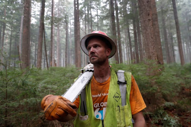 Matt Meyers, part of the Hillbilly Brigade of some 1,200 men and women who spontaneously came together to fight fires, poses with his chainsaw in a forest during the aftermath of the Riverside Fire near Molalla, Oregon