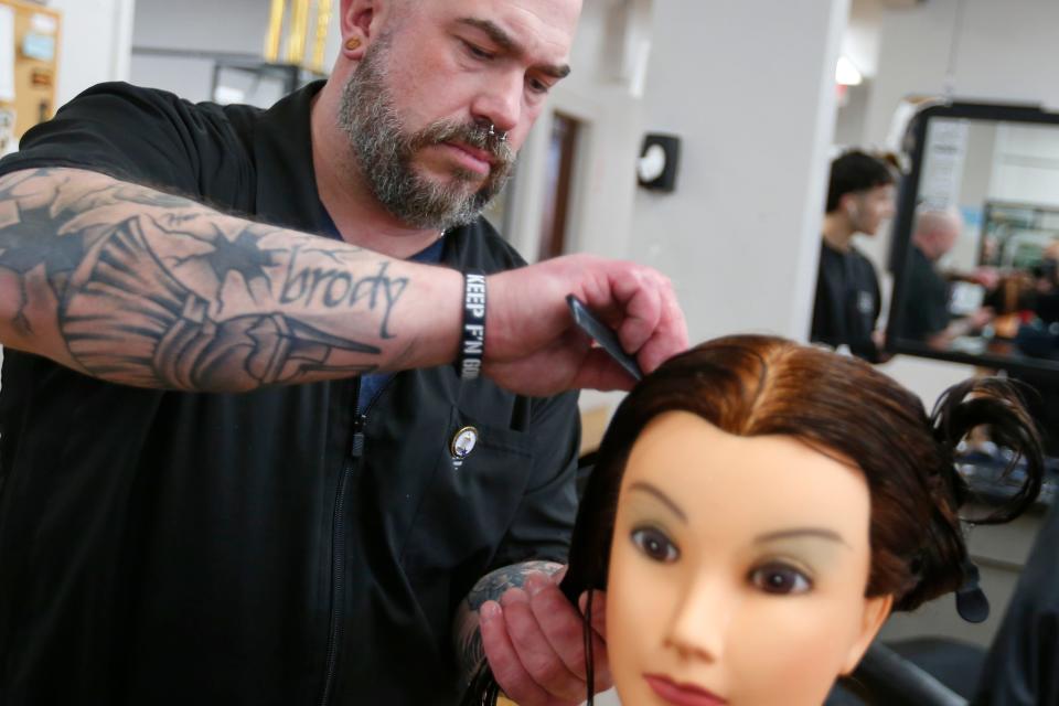 Chris Anderson works on his haircutting technique using a dummy at the Rob Roy Academy in Fall River.
