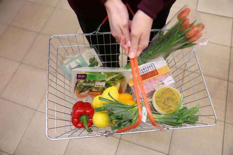 FILE PHOTO: A customer carries a basket filled with food inside a Sainsbury’s supermarket in London