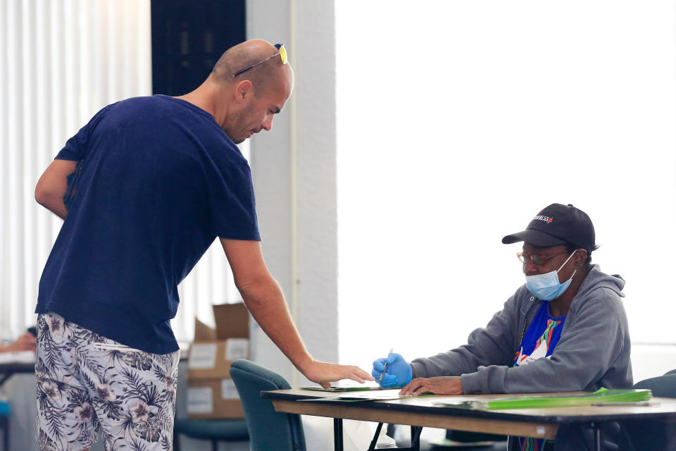 A poll worker provides a voter with a ballot during the Florida presidential primary on March 17, 2020, in Miami. (Photo: Cliff Hawkins via Getty Images)