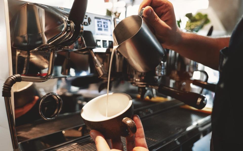 Barista preparing coffee with steamed milk - www.alamy.com