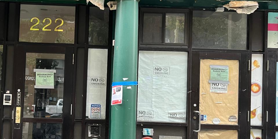 A storefront of a closed building with paper all over the windows and signs warning of rat poision.