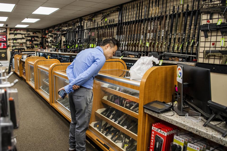 FILE — A customer browses the guns on display at SP firearms, June 23, 2022, in Hempstead, New York. A sweeping new gun law in New York that would require applicants to hand over social media information before they could carry a gun in public while declaring bucolic parks, bustling Times Square and a long list of other places off limits for firearms is scheduled to take effect on Thursday, Sept. 1, 2022, amid legal battles and lingering confusion. (AP Photo/Brittainy Newman, File)