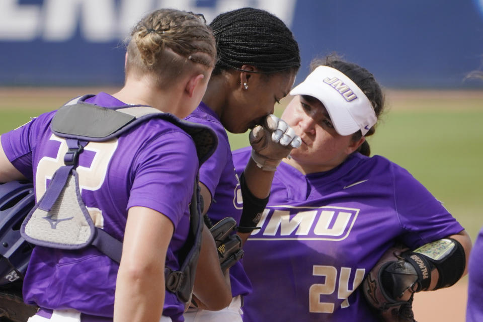 James Madison's Odicci Alexander, center, stands with teammates Lauren Bernett (22) and Lynsey Meeks (24) as she is taken out as pitcher in the fifth inning of an NCAA Women's College World Series softball game against Oklahoma, Monday, June 7, 2021, in Oklahoma City. (AP Photo/Sue Ogrocki)