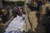 FILE- Palestinians bury the bodies of their relatives, killed in the Israeli bombardment of the Gaza Strip, Monday, Oct. 23, 2023, at a cemetery in Deir Al-Balah, Gaza, As the fifth Israel-Hamas war rages, growing more deadly and devastating, international and local monitoring groups in besieged Gaza have been unable to keep up. (AP Photo/Hatem Moussa, File)
