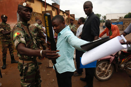 Malian soldiers carry out checks as people wait at a polling station before the polls open during a presidential run-off election in Bamako, Mali August 12, 2018. REUTERS/Luc Gnago