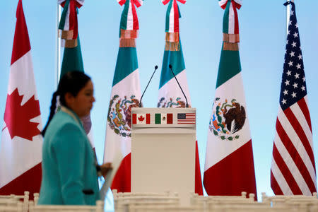 FILE PHOTO - A woman walks by the flags of Canada, Mexico and the U.S. before a joint news conference on the closing of the seventh round of NAFTA talks in Mexico City, Mexico March 5, 2018. REUTERS/Edgard Garrido