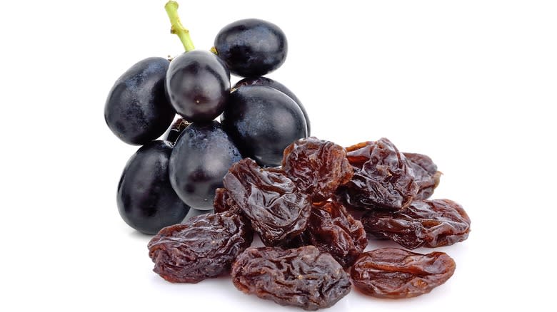 Small bunch of grapes next to pile of raisins