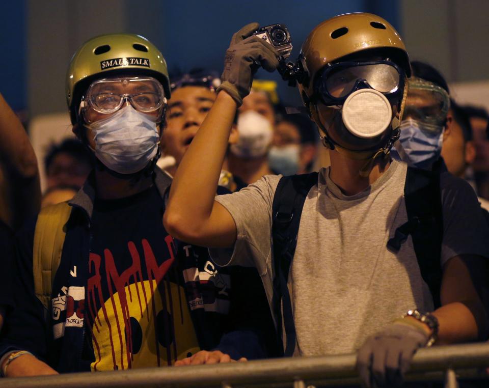 A pro-democracy protester takes a photo with a camera attached to his helmet during a standoff with riot police in the Mongkok shopping district of Hong Kong early October 19, 2014. Violent clashes erupted early on Sunday in a Hong Kong protest hotspot as unarmed pro-democracy activists once again confronted riot police despite the confirmation of talks between protest leaders and officials early this week. REUTERS/Bobby Yip (CHINA - Tags: POLITICS CIVIL UNREST)