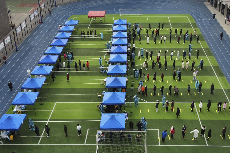 In this photo released by Xinhua News Agency, residents line up on a football field for the coronavirus test during a mass testing in north China's Tianjin municipality, Sunday, Jan. 9, 2022. Tianjin, a major Chinese city near Beijing has placed its 14 million residents on partial lockdown after 41 children and adults tested positive for COVID-19, including at least two with the omicron variant. (Sun Fanyue/Xinhua via AP)