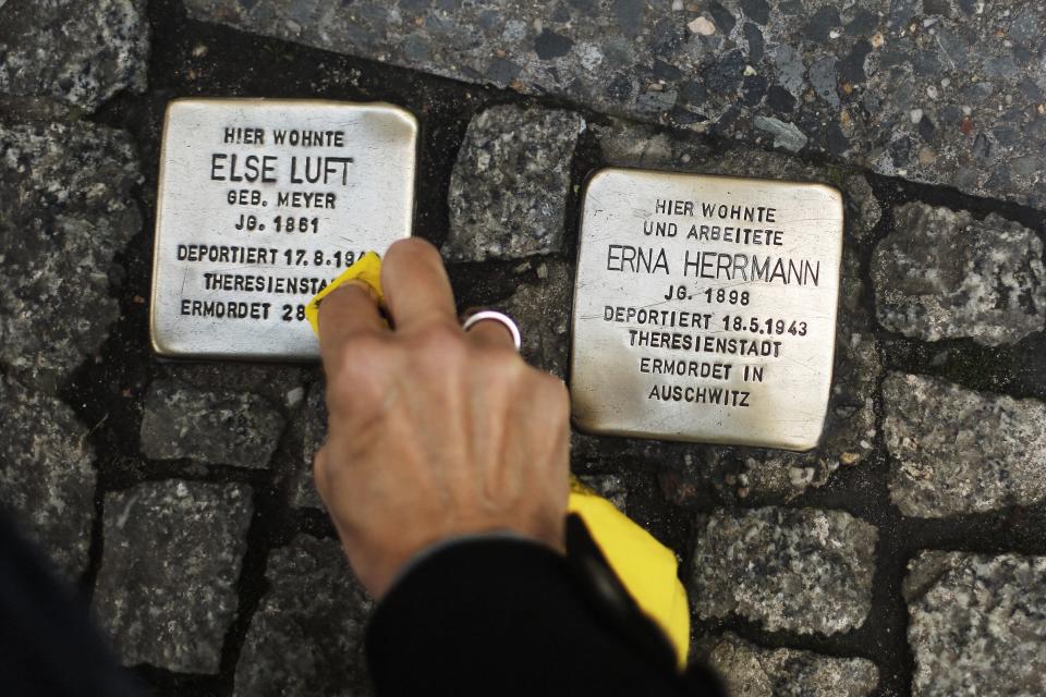 FILE - In this Nov. 9, 2013 file picture a woman cleans a so called 'Stolperstein', or stumbling stone, set by German artist Gunter Demnig, to remember Nazi victims in Berlin, Germany. The epicenter of the Holocaust, the city where Hitler signed the death warrants of 6 million Jews, seems an unlikely candidate for the world’s fastest growing Jewish community. But despite this stigma of Nazism, Berlin’s dynamic, prosperous present and its rich, pre-World War II Jewish past initially attracted an influx from the former Soviet Union and has continued with the arrival of thousands of Israelis and smaller numbers of often young immigrants from Australia, France, the United States and elsewhere. (AP Photo/Markus Schreiber,File)