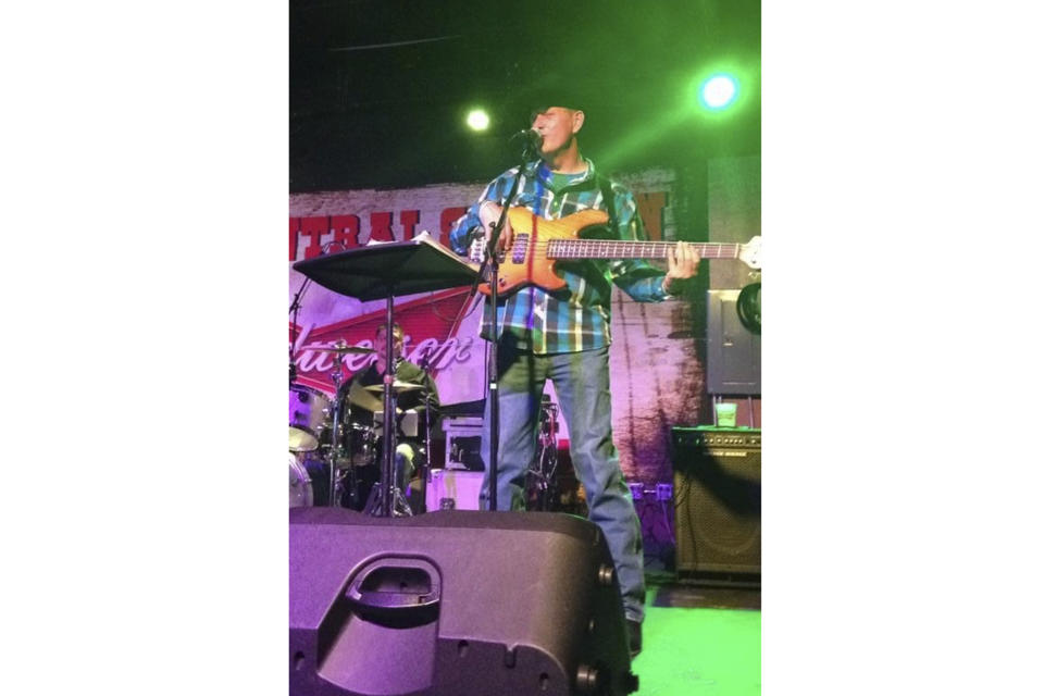 This undated image provided by Hilary Mallak shows her father, Patrick Pearson, during one of his gigs as a musician. Pearson was found dead outside of the Swiss Chalet Inn in Ruidoso, New Mexico, where he lived after smoke and flames from a pair of fast-moving wildfires moved into the community. Thousands of residents were forced to evacuate and authorities have estimated 1,400 structures have been damaged or destroyed. (Hilary Mallak via AP)