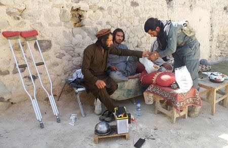 An Afghan police medic treats an injured policeman who was wounded in a military operation against suspected Islamic State militants in Achin district of Nangarhar province, in eastern Afghanistan, April 14, 2017. REUTERS/Parwiz