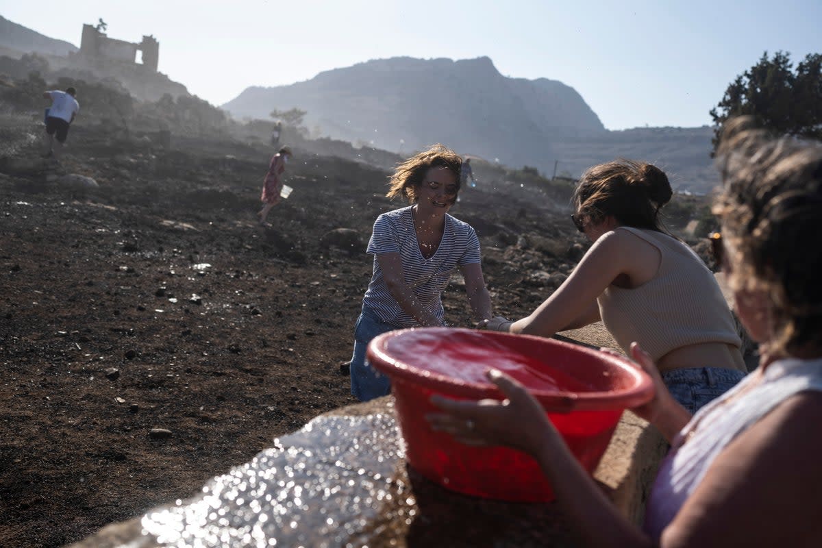 German tourists together with local residents try to extinguish a fire near the seaside resort of Lindos (AP Photo/Petros Giannakouris)