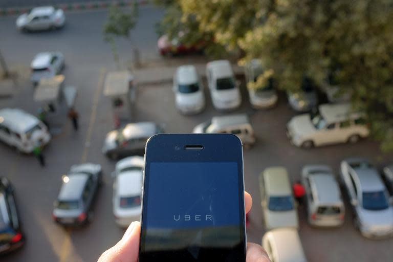 The Uber smartphone app, used by customers to book taxis using its service, is pictured over a parking lot in the Indian capital New Delhi