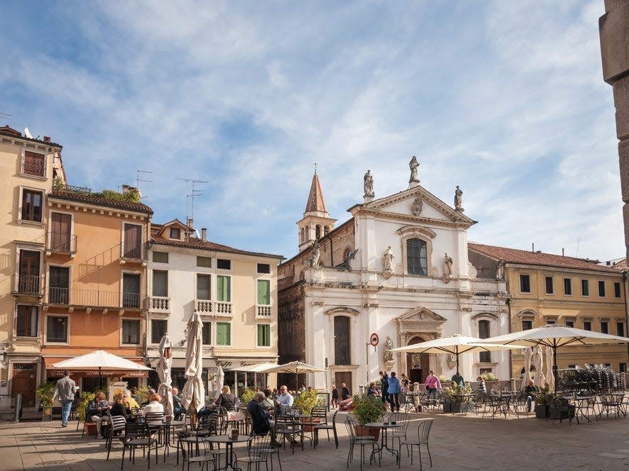 People sitting at tables in a square in Vicenza, Italy.