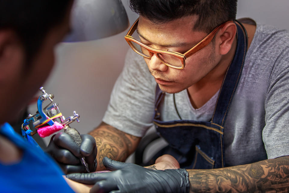 A tattoo artist working on a client