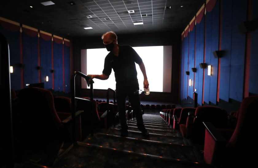 LA MESA, CA - SEPTEMBER 3: Wayne Price cleans handrails in a movie theater on the first day of being open since the closing due to the coronavirus pandemic at Reading Cinemas Grossmont on Thursday, Sept. 3, 2020 in La Mesa, CA. (K.C. Alfred / The San Diego Union-Tribune)