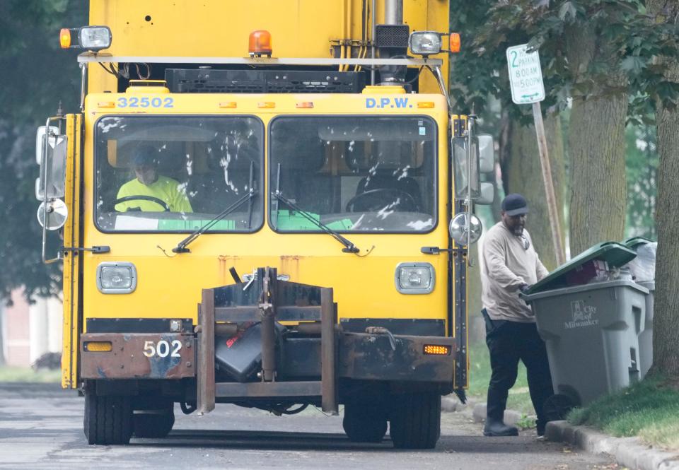 City of Milwaukee sanitation driver Joe Langford (left) carries a trash bin to the truck as Sequetia Smith drives on North 72nd Street in Milwaukee on Wednesday, June 28, 2023. The quality of Wisconsin's unhealthy air continues from Canadian wildfires.
