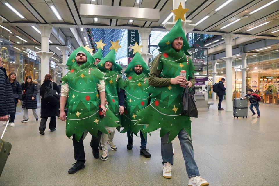 Passengers dressed as Christmas trees at St Pancras (PA)