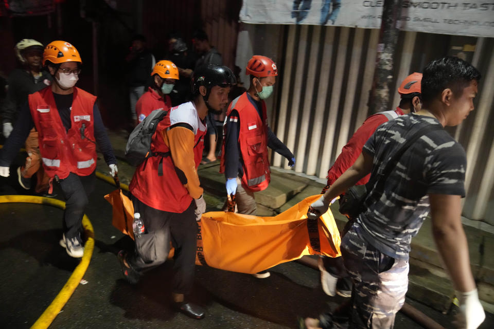 Rescuers carry the body of a victim of a fire in Jakarta, Indonesia, Friday, March 3, 2023. A large fire broke out at a fuel storage depot in Indonesia’s capital on Friday, killing several people, injuring dozens of others and forcing the evacuation of thousands of nearby residents after spreading to their neighborhood, officials said. (AP Photo/Dita Alangkara)
