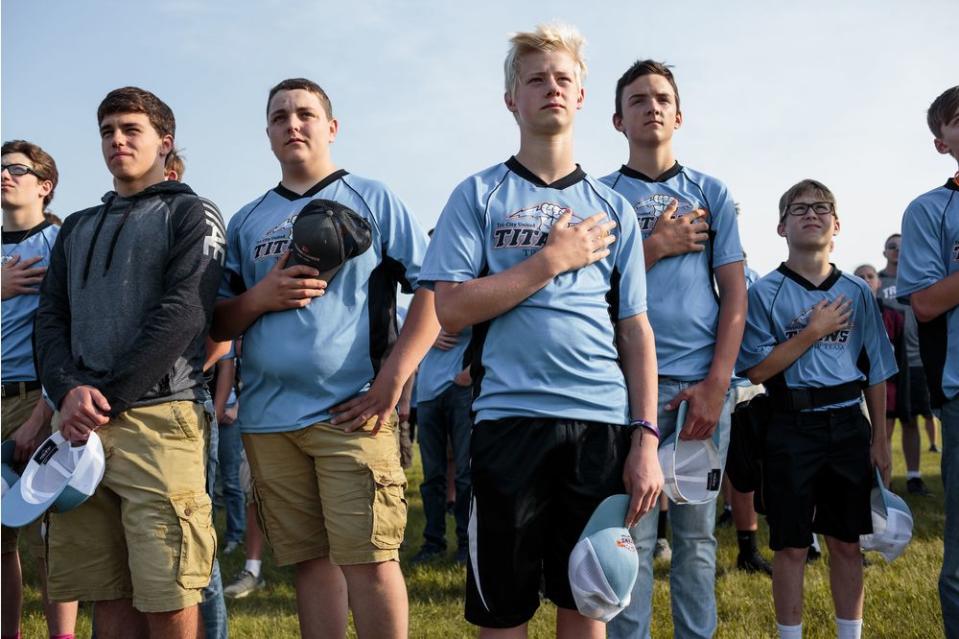 Students from Tri-City United High School stand for the Pledge of Allegiance early in the morning on June 15, 2018, before beginning to compete in the annual trap shooting championship in Alexandria, Minnesota.