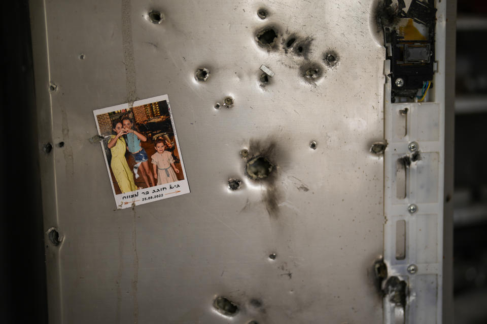A photo hangs on a refrigerator next to bullet holes in a house at Kibbutz Kissufim in southern Israel, Saturday, Oct. 21, 2023. The Kibbutz was overrun by Hamas militants from the nearby Gaza Strip on Oct. 7, when they killed and captured many Israelis. (AP Photo/Francisco Seco)