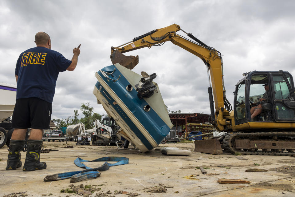 Harahan firefighter Jake Razzio, left, went to Slidell to help clear debris on Thursday, April 11, 2024, the day after a tornado hit parts of the area. Razzio directs Kevin Vino, right, as he attempts to flip over a 25-foot boat at Scotty's Performance Boat & Marine Thursday, April 11, 2024, in Slidell, La., after a tornado hit a day earlier. (Chris Granger/The Times-Picayune/The New Orleans Advocate via AP)