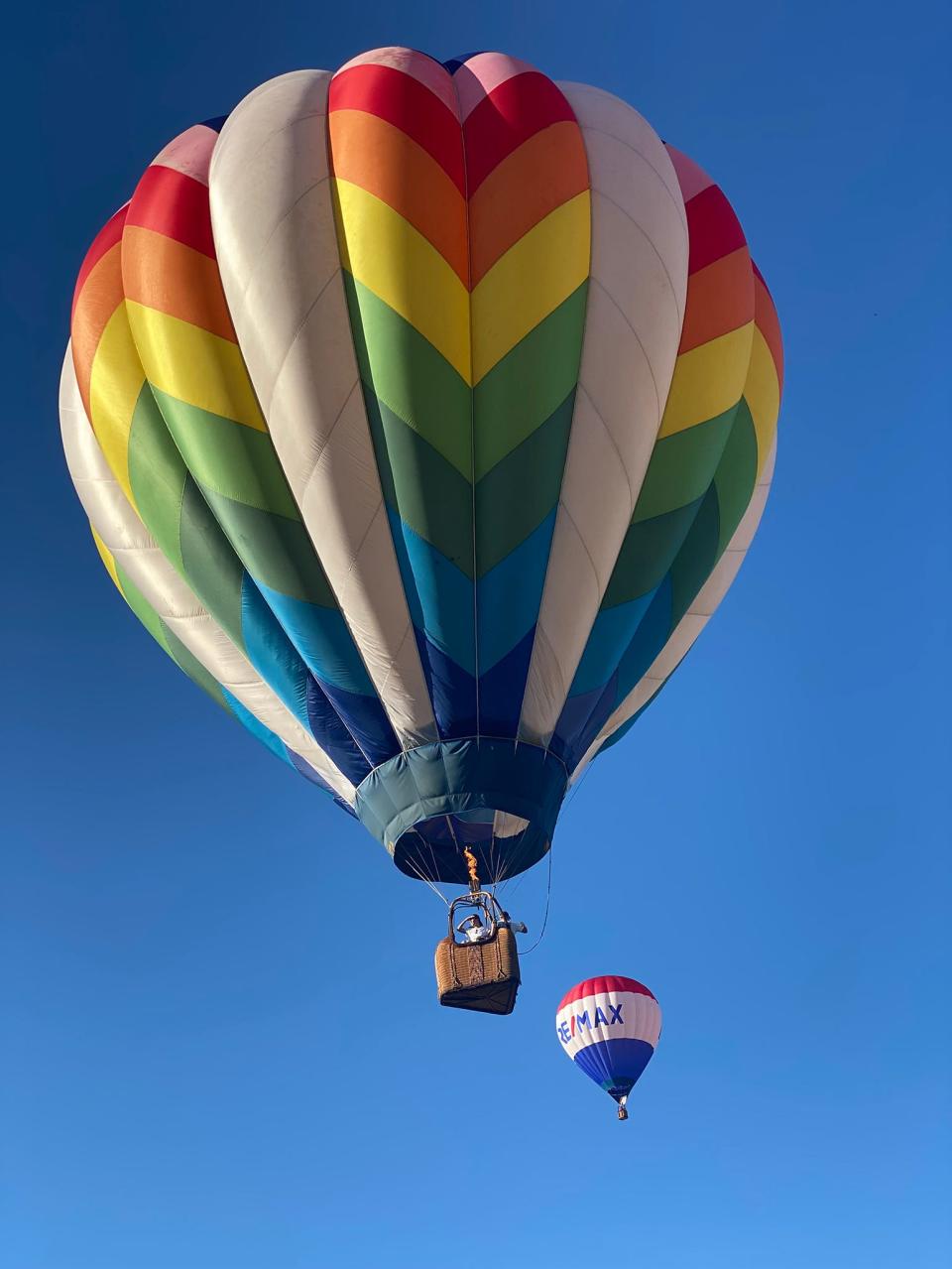 Pilot Bill Sherner flies God's Promise in the foreground with one of two Re/Max balloons in the background in a Michigan Challenge Balloonfest evening launch Friday, June 24, 2022.