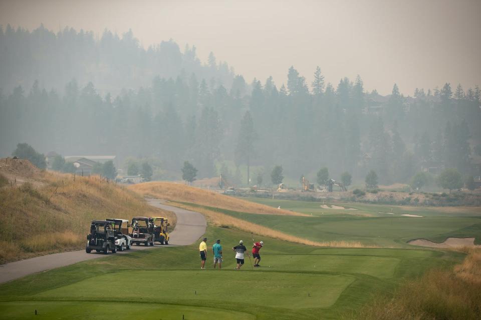 Thick smoke from wildfires blankets the area as people play golf. THE CANADIAN PRESS/Darryl Dyck