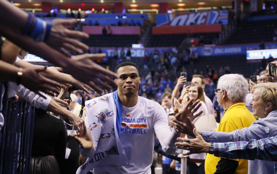 Oklahoma City Thunder guard Russell Westbrook slaps hands with fans as he leaves the floor after an NBA basketball game against the Milwaukee Bucks in which he tied the record for triple-doubles in a season in Oklahoma City, Tuesday, April 4, 2017. Oklahoma City won 110-79. (AP Photo/Sue Ogrocki)